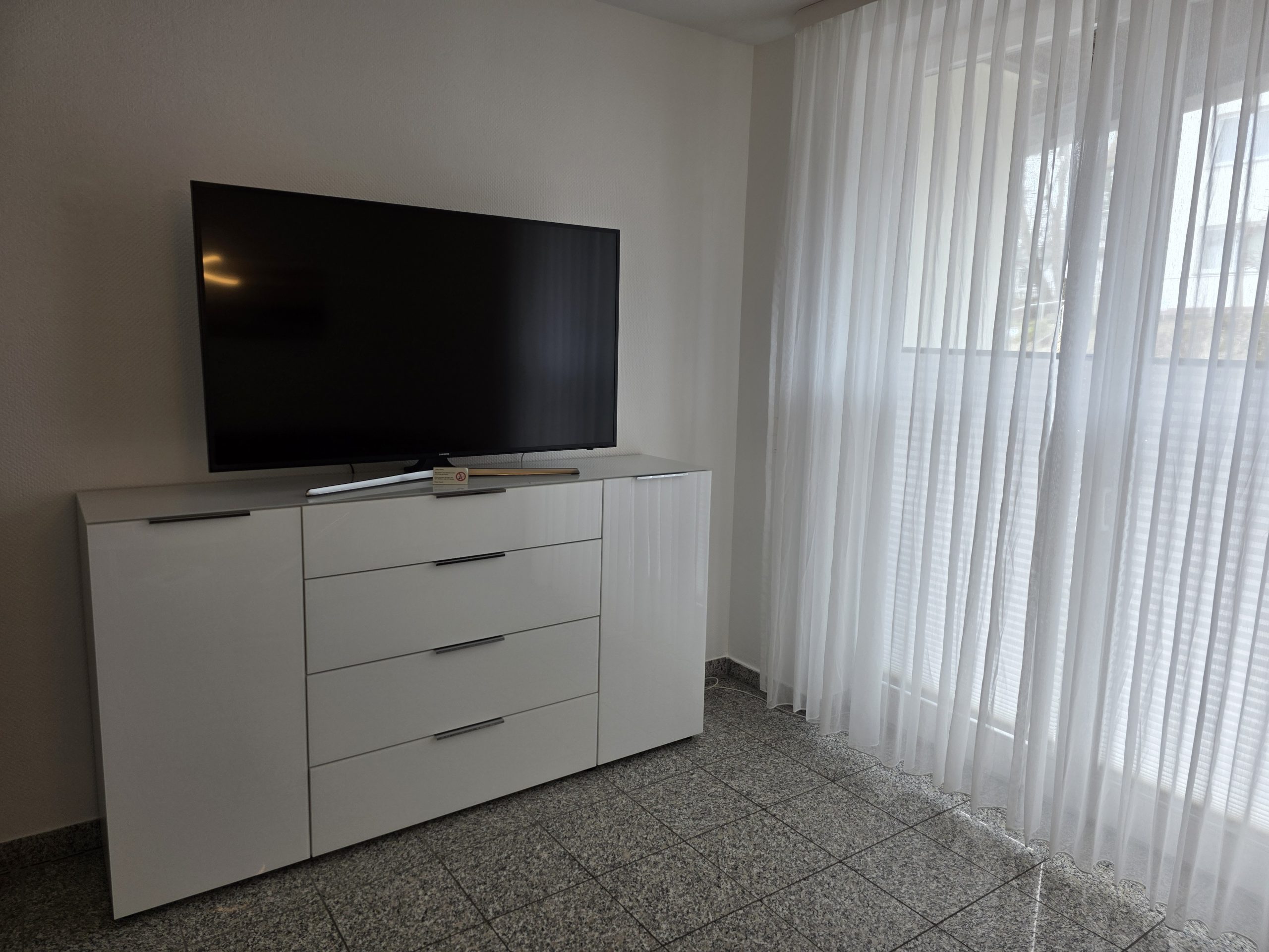 TV im Wohnzimmer mit angrenzendem Balkon