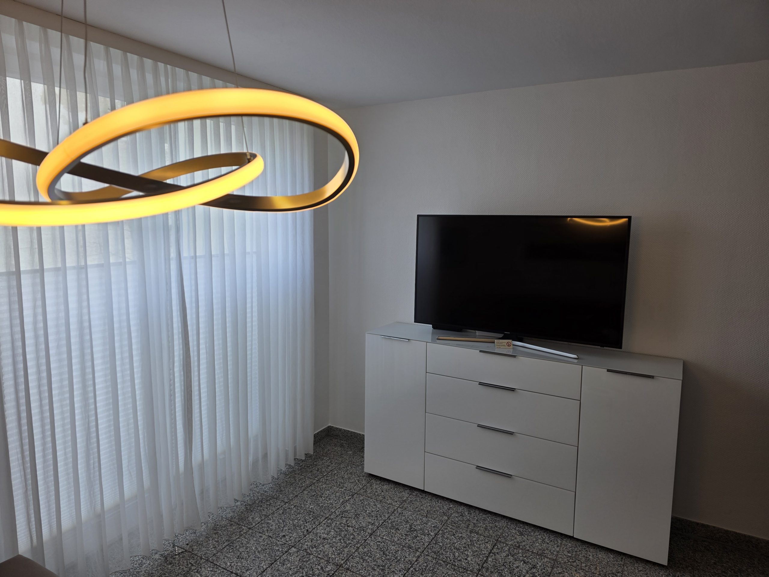 TV im Wohnzimmer mit angrenzendem Balkon